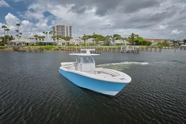  Yacht Photos Pics 2015 Invincible 36 boat on calm water near coastal homes and palm trees.