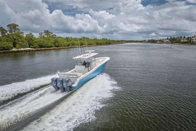  Yacht Photos Pics 2015 Invincible 36 boat cruising on a scenic river under cloudy skies.