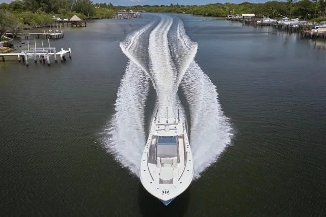  Yacht Photos Pics Invincible 36 boat cruising on a river, 2015 model, creating a wide wake.