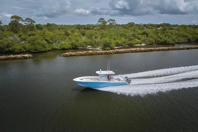  Yacht Photos Pics Invincible 36 boat cruising on a river, 2015 model, surrounded by lush greenery.