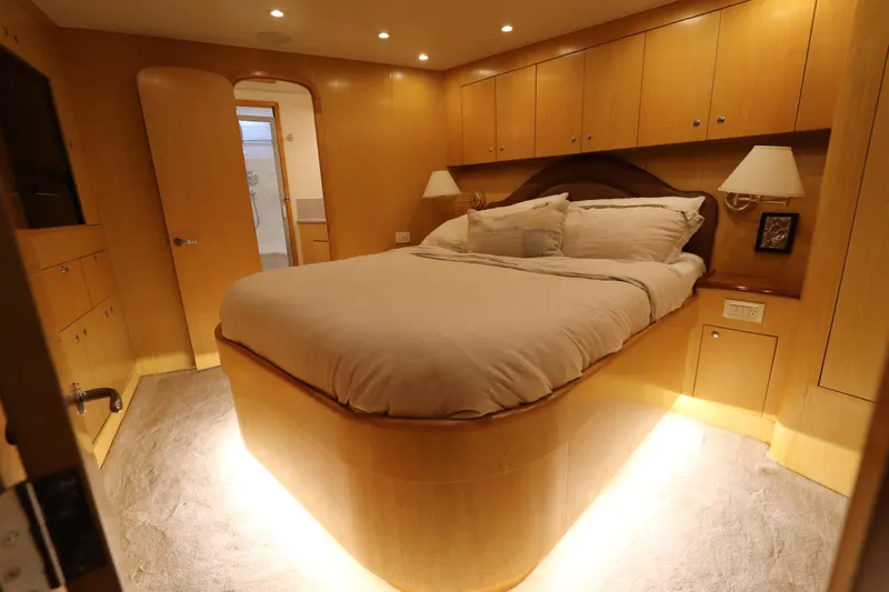 Bolita Yacht Photos Pics Luxurious bedroom interior of 2002 Buddy Davis 74 yacht with cozy lighting and elegant wood finish.