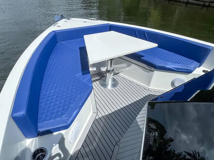  Yacht Photos Pics 2024 De Antonio Yachts D28 Open with blue seating and a white table on deck.