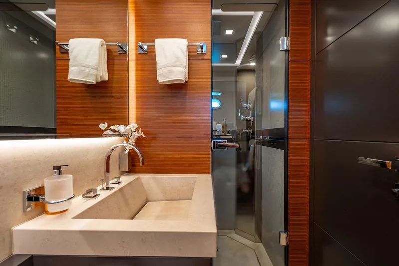 Mixed Emotions Yacht Photos Pics Luxurious bathroom in 2014 Mangusta 110 yacht with modern fixtures and elegant wood paneling.