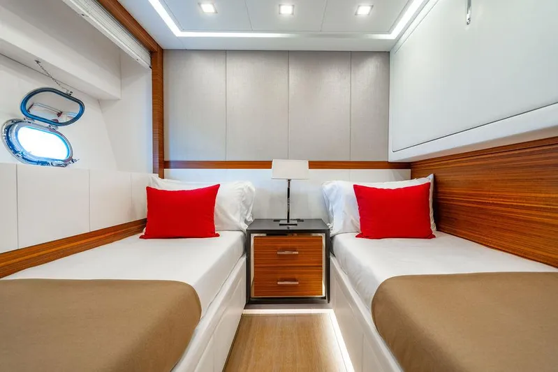 Mixed Emotions Yacht Photos Pics Luxurious 2014 Mangusta 110 yacht cabin with twin beds, red pillows, and modern wood accents.