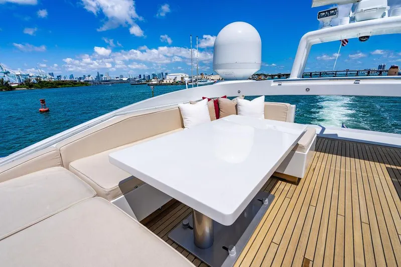 Mixed Emotions Yacht Photos Pics Luxurious 2014 Mangusta 110 yacht deck with seating, table, and ocean view.