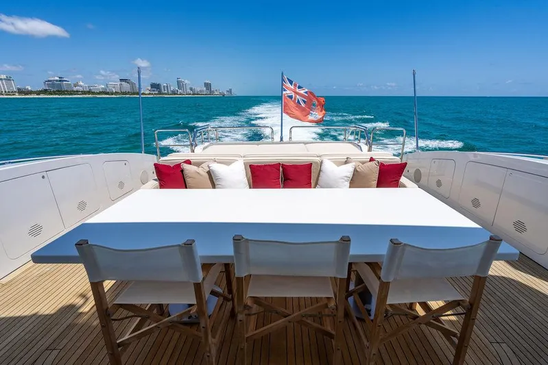 Mixed Emotions Yacht Photos Pics Luxurious 2014 Mangusta 110 yacht deck with dining area, ocean view, and flag.