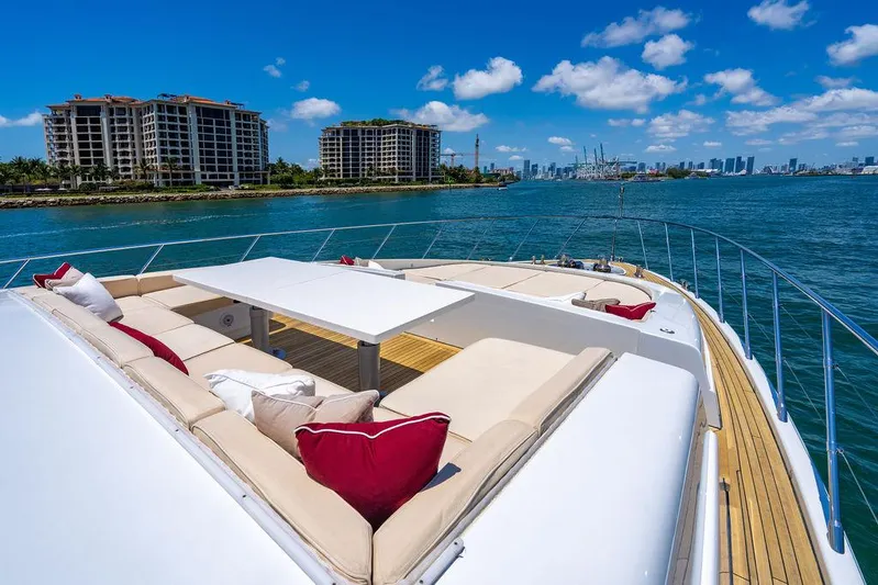 Mixed Emotions Yacht Photos Pics Luxurious 2014 Mangusta 110 yacht deck with plush seating, overlooking waterfront cityscape.