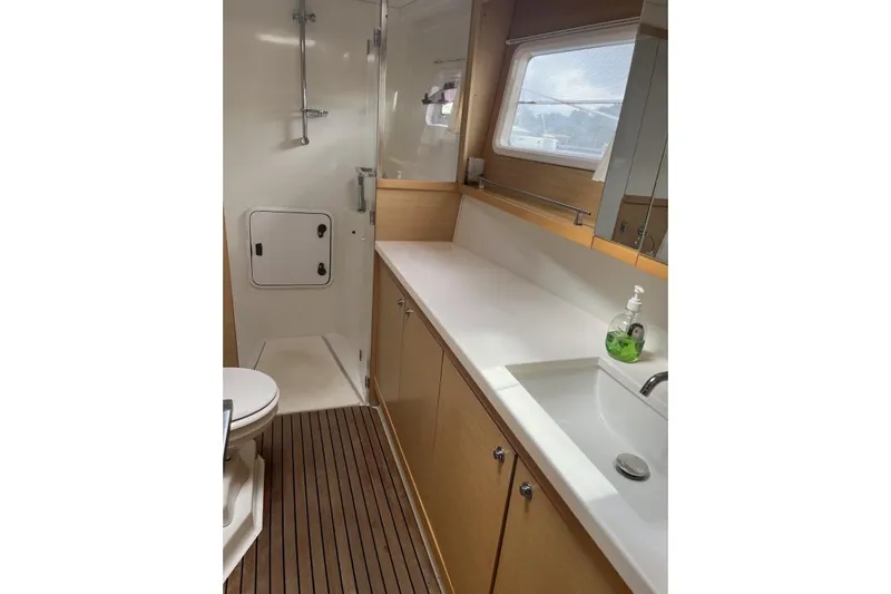 Searching For Bliss Yacht Photos Pics Bathroom interior of 2011 Lagoon 450 F yacht, featuring shower, sink, and wooden flooring.