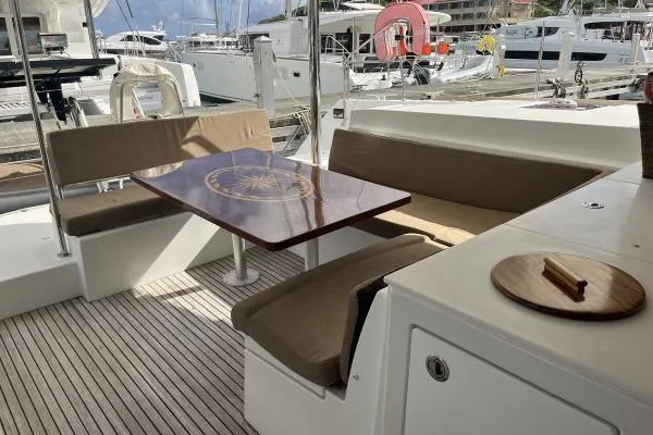 Searching For Bliss Yacht Photos Pics Outdoor seating area on a 2011 Lagoon 450 F yacht with wooden table and cushioned benches.