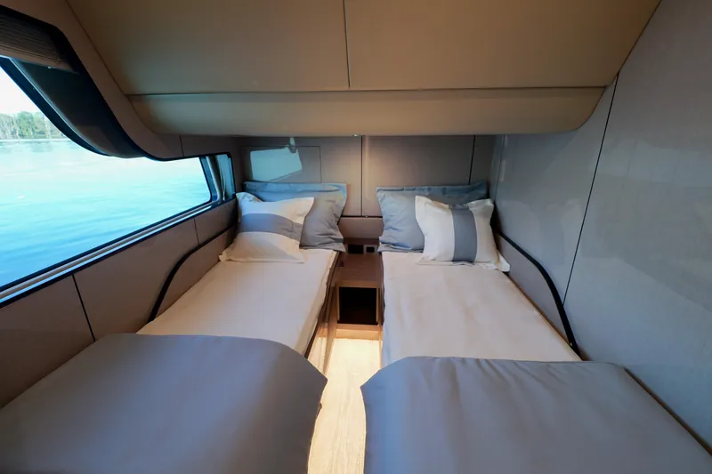  Yacht Photos Pics Luxurious twin cabin interior on 2026 Cruisers Yachts 57 Fly, featuring elegant bedding and scenic window view.