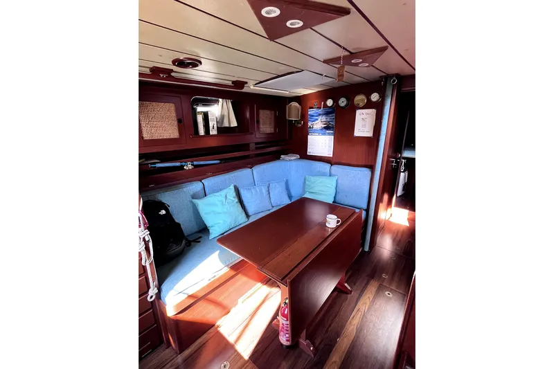 Arma Di Re Yacht Photos Pics Cozy interior of 1983 Hallberg-Rassy 42E sailboat with blue cushions and wooden table.