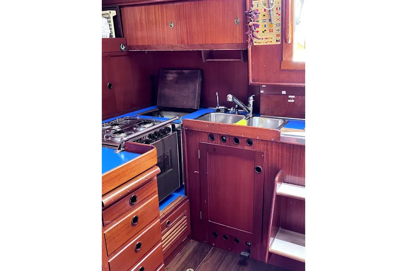 Arma Di Re Yacht Photos Pics 1983 Hallberg-Rassy 42E yacht kitchen with wooden cabinetry and blue countertops.