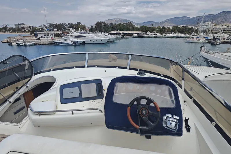  Yacht Photos Pics Cockpit view of 2001 Sunseeker Manhattan 74 yacht in marina, with scenic mountain backdrop.