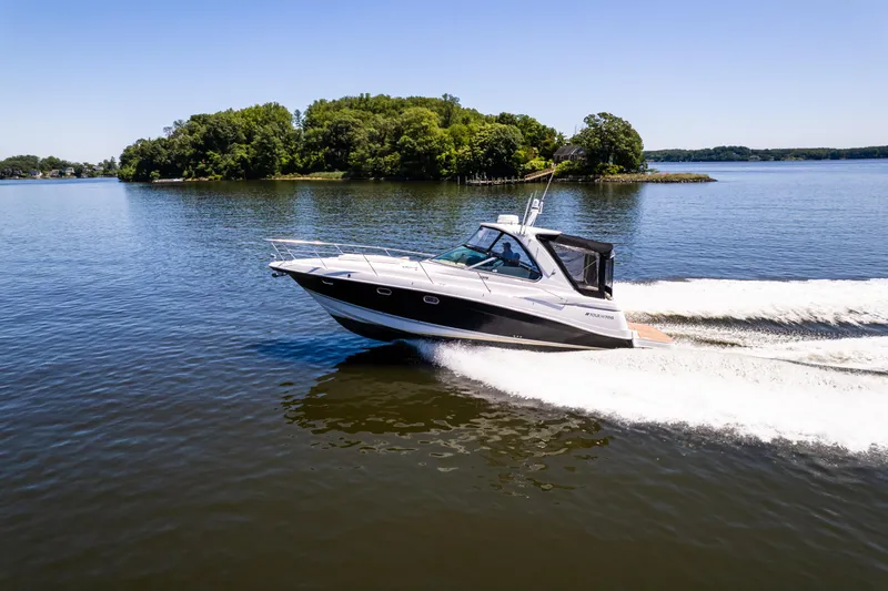 Four Fans Yacht Photos Pics 2008 Four Winns V378 boat cruising on a serene lake with lush green island backdrop.