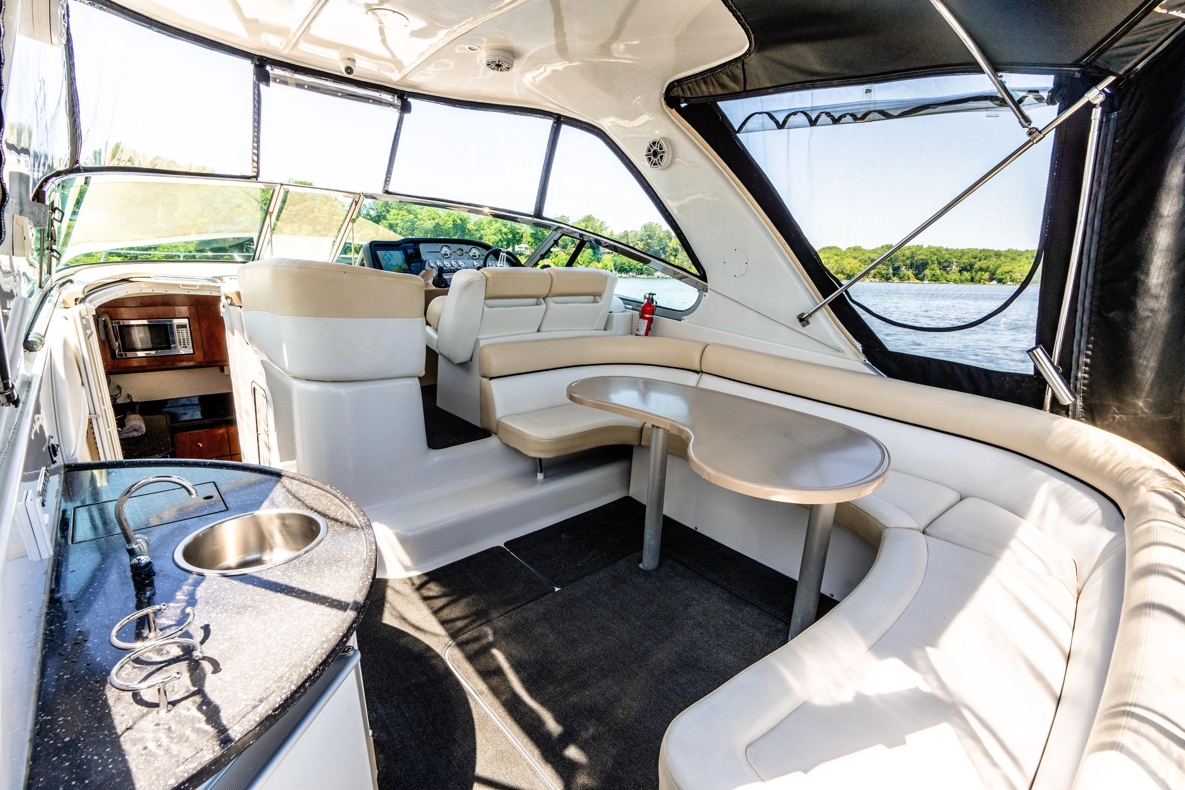 Four Fans Yacht Photos Pics 2008 Four Winns V378 yacht interior with seating, table, and kitchenette, overlooking water.