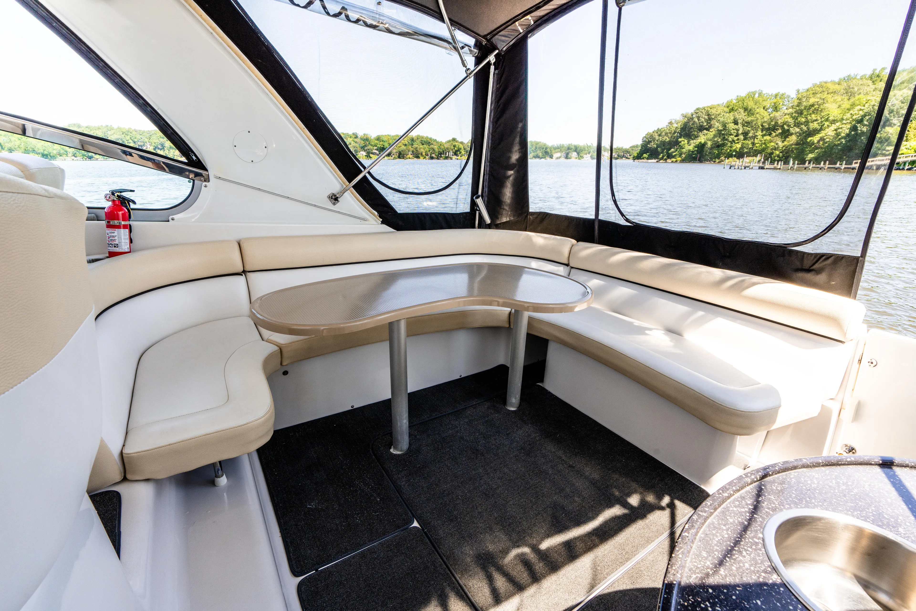 Four Fans Yacht Photos Pics 2008 Four Winns V378 boat interior with curved seating and table, overlooking a serene lake.