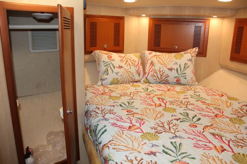  Yacht Photos Pics 2005 Cabo Flybridge CAT C18 cabin with colorful coral-themed bedding and wooden accents.