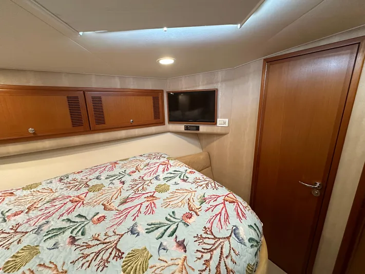  Yacht Photos Pics Interior of 2005 Cabo Flybridge CAT C18 with bed, TV, and wooden cabinets.