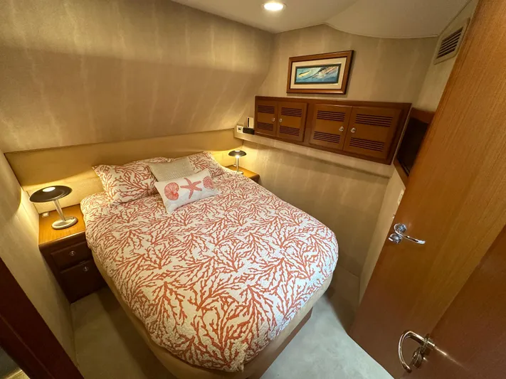  Yacht Photos Pics Cozy bedroom in 2005 Cabo Flybridge CAT C18 yacht with coral-patterned bedding and wooden cabinets.