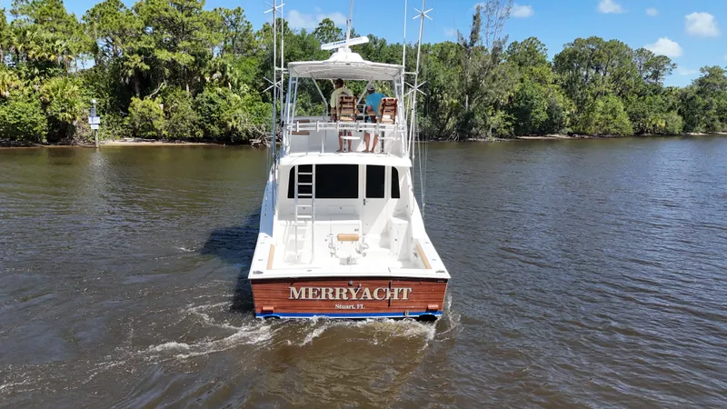  Yacht Photos Pics 2005 Cabo Flybridge CAT C18 yacht cruising on a river, surrounded by lush greenery.