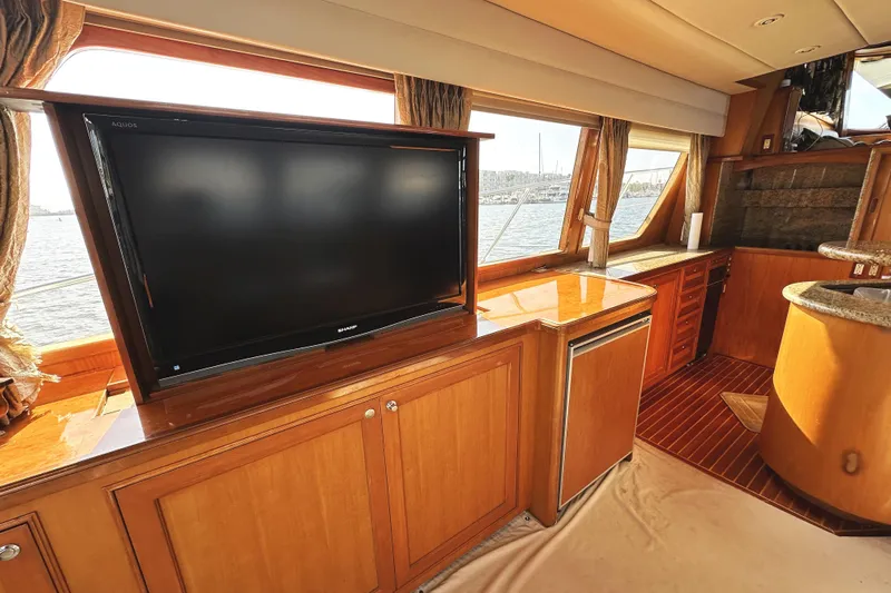 Times Like These Yacht Photos Pics Luxurious interior of 2004 McKinna 57 PHMY yacht with large TV and wooden cabinetry.