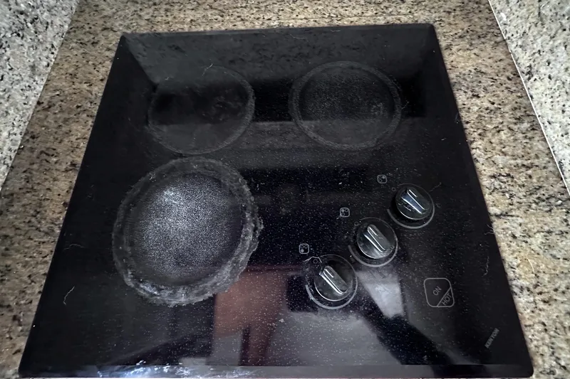 Times Like These Yacht Photos Pics Black stovetop with four burners and control knobs on a granite countertop.