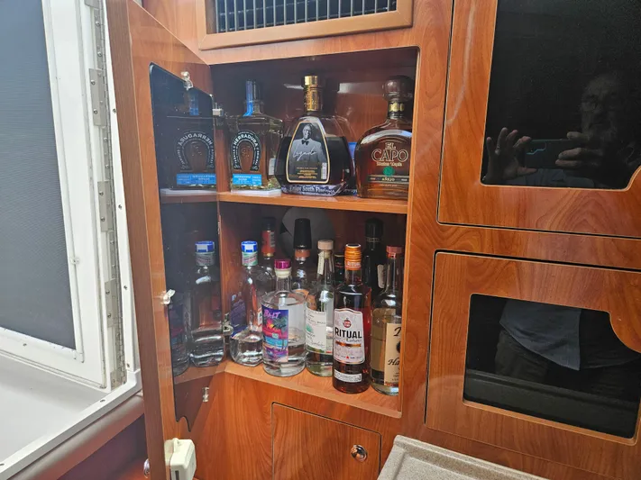  Yacht Photos Pics Liquor cabinet inside a 2005 Four Winns 378 Vista boat, featuring various bottles.