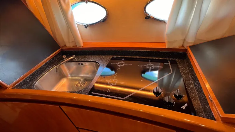 1691 Yacht Photos Pics Compact kitchen area in a 2000 Princess V65 yacht with sink and stovetop.