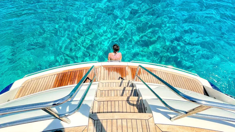 1691 Yacht Photos Pics Person relaxing on a Princess V65 yacht, overlooking clear turquoise water.