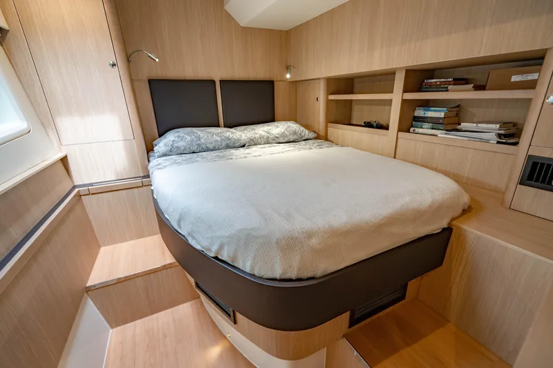 Altair Yacht Photos Pics Luxurious bedroom interior of 2019 Aquila 44 Yacht with cozy bed and wooden shelves.