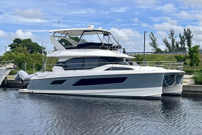 Altair Yacht Photos Pics 2019 Aquila 44 Yacht docked on a calm waterway, surrounded by greenery.