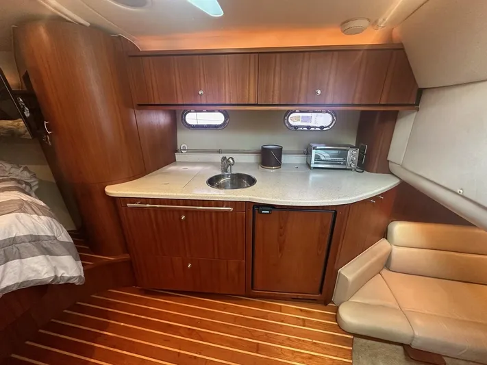 Five Too Soon Yacht Photos Pics 2008 Tiara Yachts 3500 Sovran interior with kitchenette, featuring wood cabinetry and compact appliances.