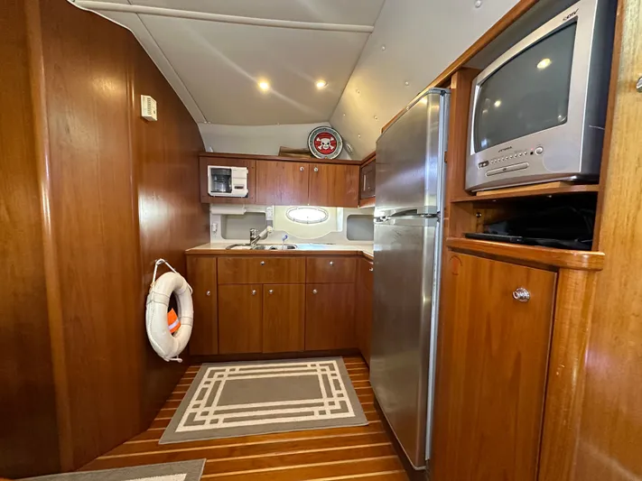 Hoggtide Two Yacht Photos Pics 1998 Tiara Yachts 4100 Open kitchen with wood cabinets, stainless steel fridge, and TV.