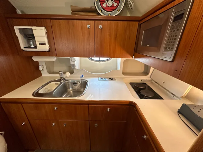 Hoggtide Two Yacht Photos Pics 1998 Tiara Yachts 4100 Open kitchen with wooden cabinets, sink, stove, and microwave.