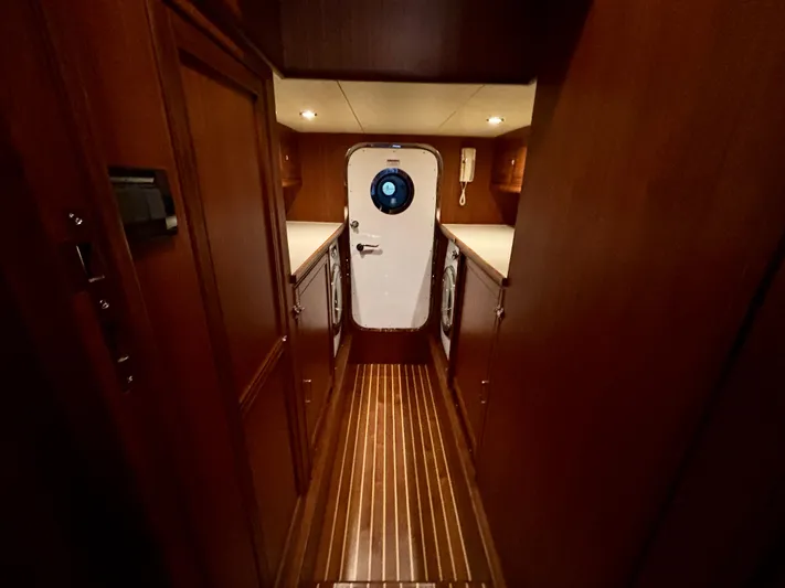 Forever Fun Yacht Photos Pics Narrow hallway inside 2018 Marlow 53E CB yacht with wooden cabinetry and porthole door.