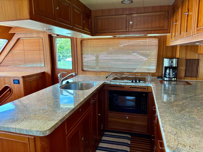 Forever Fun Yacht Photos Pics Luxurious Marlow 53E CB 2018 yacht kitchen with granite countertops and wooden cabinetry.