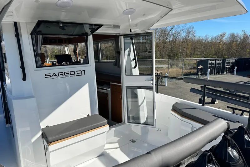  Yacht Photos Pics 2025 Sargo 31OB boat interior with open door, outdoor seating, and wooded background.