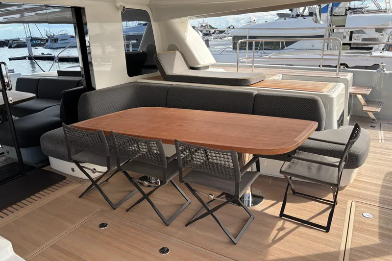 Sixty7 Yacht Photos Pics Luxurious 2023 Lagoon SIXTY 7 yacht deck with elegant dining area and marina view.
