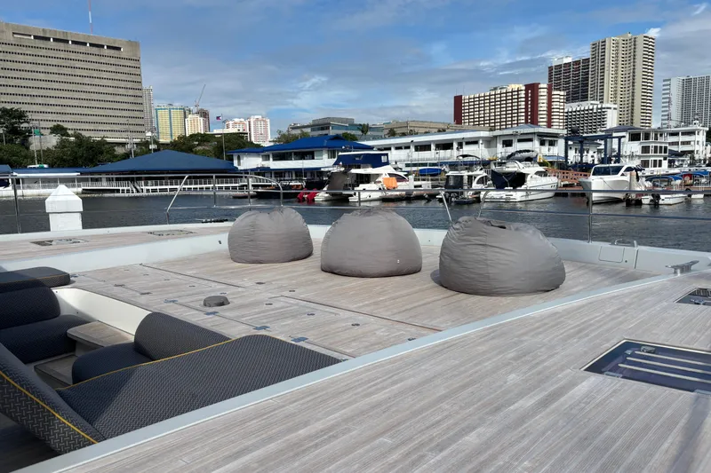 Sixty7 Yacht Photos Pics 2023 Lagoon SIXTY 7 yacht deck with bean bags, docked in urban marina.