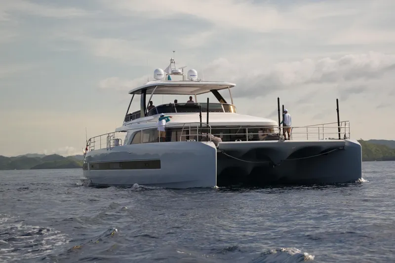 Sixty7 Yacht Photos Pics 2023 Lagoon SIXTY 7 yacht cruising on open water with scenic background.