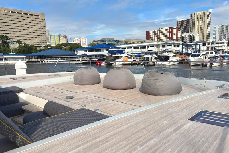 Sixty7 Yacht Photos Pics 2023 Lagoon SIXTY 7 yacht deck with bean bags, docked in urban marina.