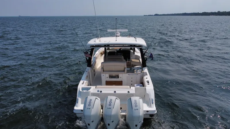  Yacht Photos Pics 2022 Boston Whaler 350 Realm boat cruising on open water, rear view.