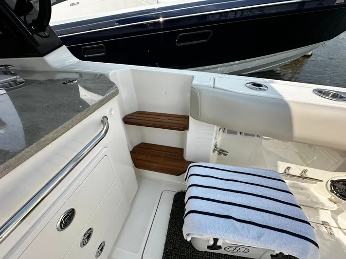  Yacht Photos Pics 2022 Boston Whaler 350 Realm interior with seating, wooden steps, and striped towel.