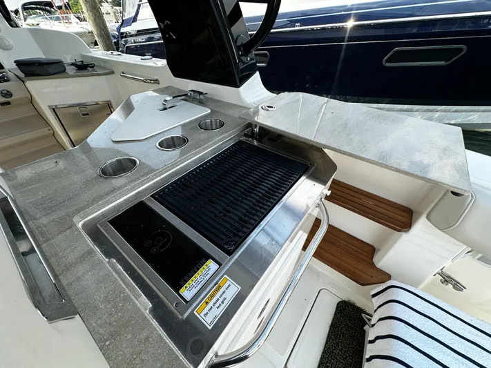 Yacht Photos Pics Outdoor kitchen on 2022 Boston Whaler 350 Realm boat with grill and cup holders.