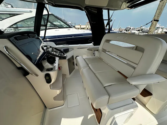  Yacht Photos Pics 2022 Boston Whaler 350 Realm interior with helm and seating, docked at marina.