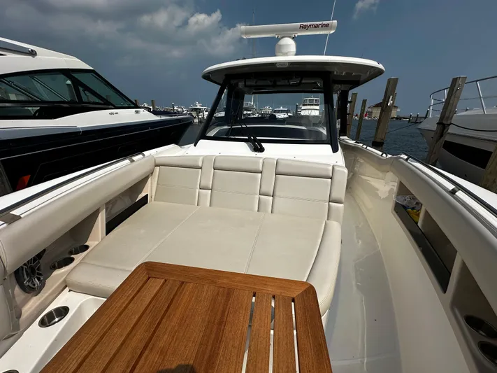  Yacht Photos Pics 2022 Boston Whaler 350 Realm boat with spacious seating and wooden table, docked at marina.