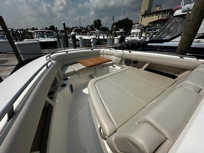  Yacht Photos Pics 2022 Boston Whaler 350 Realm boat interior with cushioned seating and wooden table.