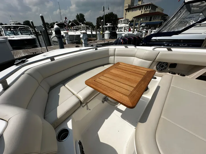  Yacht Photos Pics 2022 Boston Whaler 350 Realm boat interior with cushioned seating and wooden table at marina.
