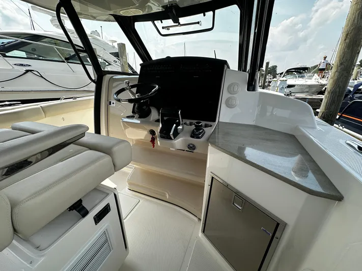  Yacht Photos Pics Interior view of 2022 Boston Whaler 350 Realm boat cockpit with steering wheel and controls.