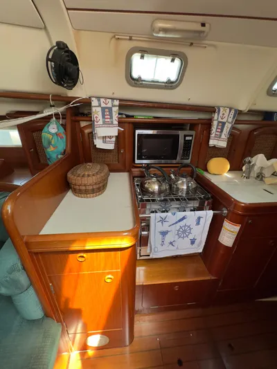  Yacht Photos Pics Interior of 2000 Beneteau 411 sailboat kitchen with stove, microwave, and wooden cabinetry.